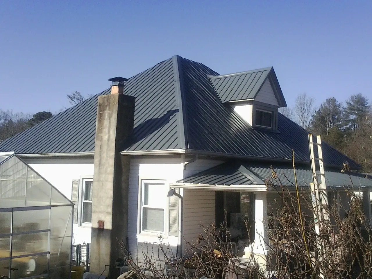 Dark blue standing seam metal roof on a white farmhouse with dormer — Slate & Tile Roof Repair by Roofing Brothers in Taos