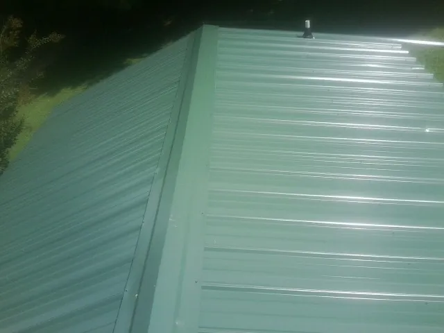 New green metal panels meeting at the ridge of a roof — Flat Roof Repair work by our crew in Taos