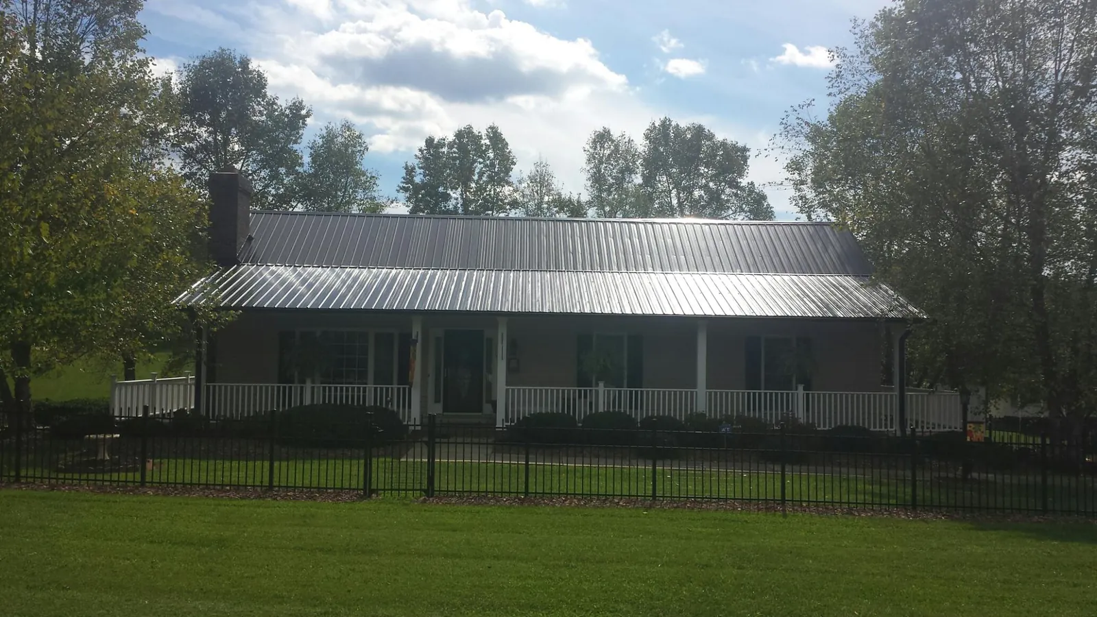 Gray metal roof on a brick ranch with a full width front porch — Gutter Guard Installation work by our crew in Taos