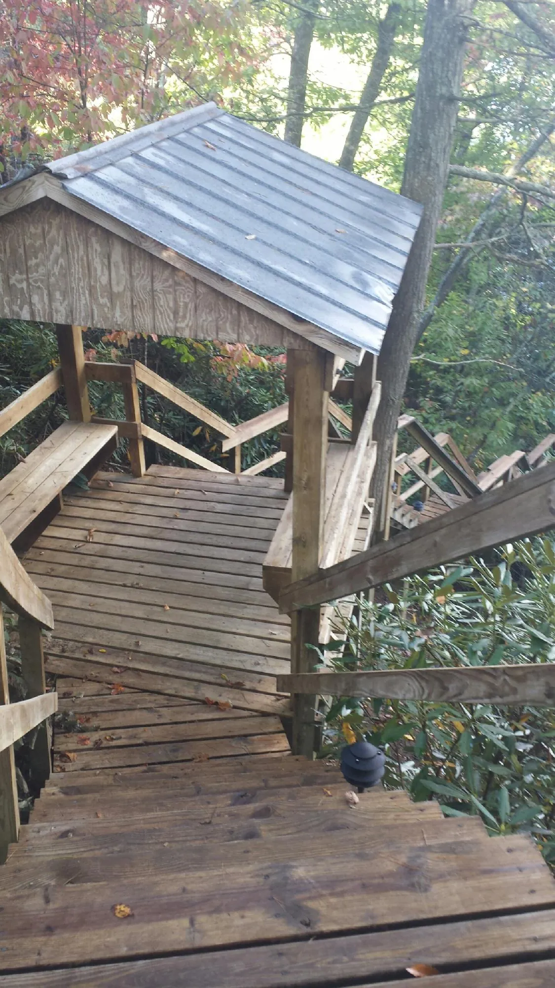 Metal roofed shelter over wooden steps on a wooded walkway — Skylight Repair & Installation work by our crew in Taos