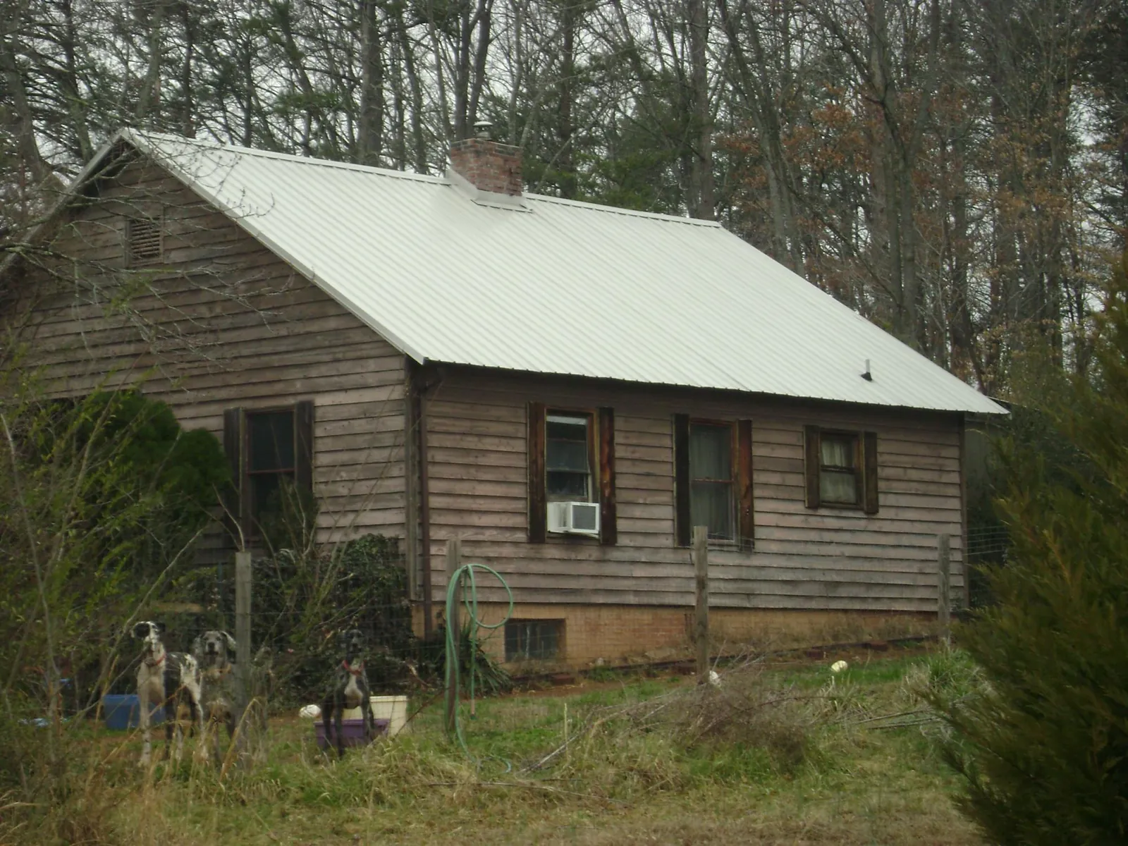 White metal roof on an old wood sided farmhouse, from a Metal Roof Installation job in Taos